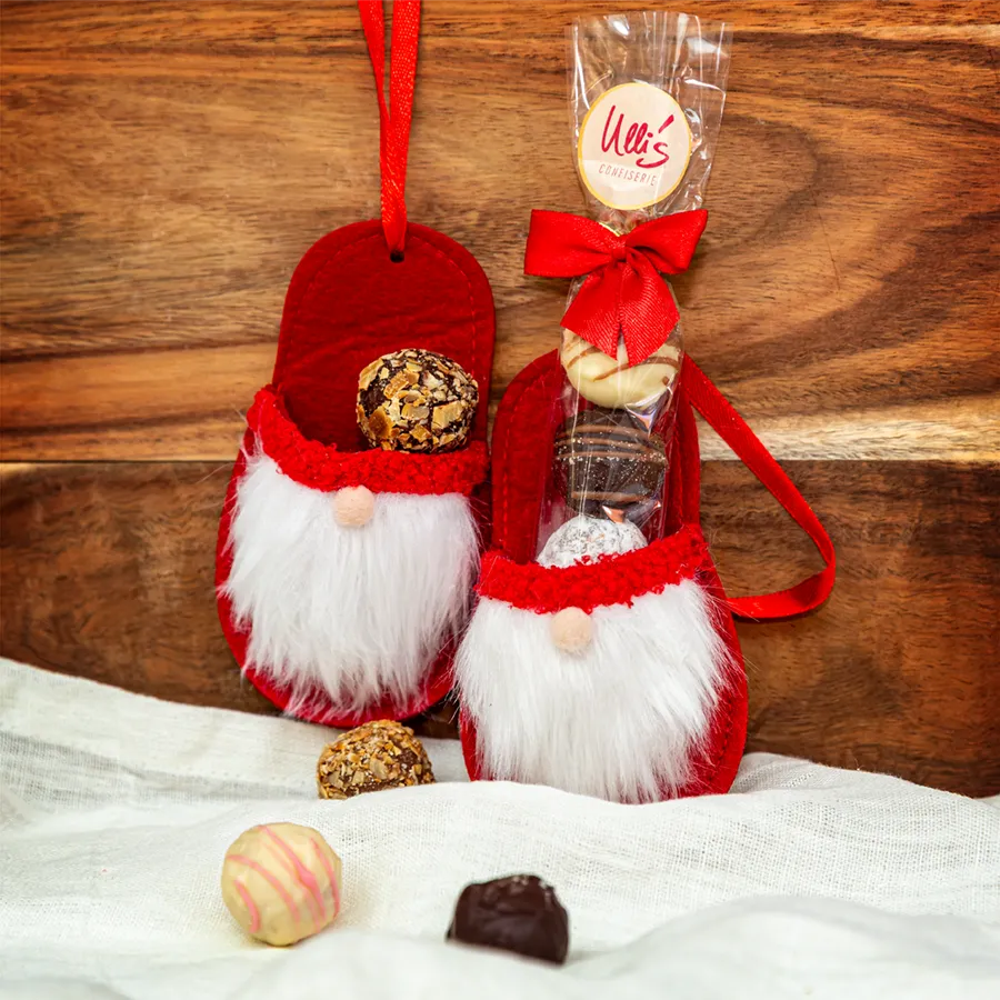 Ulli's handgemachte Pralinen in einem roten Nikolaus-Pantoffel aus Filz. Der Nikolaus hat einen weißen Vollbart und eine kleine Stupsnase.